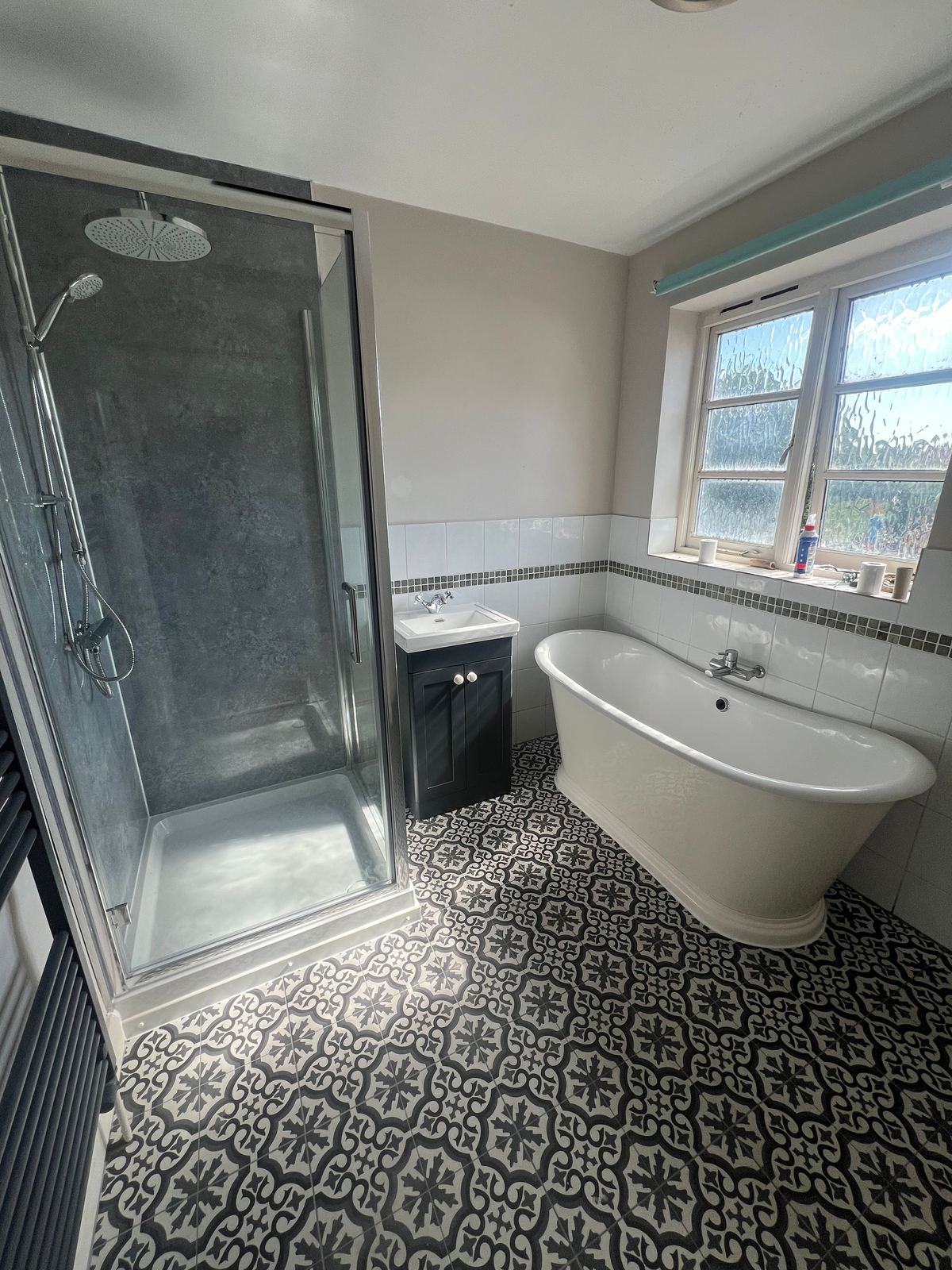 Freestanding bath and shower enclosure on patterned tiling