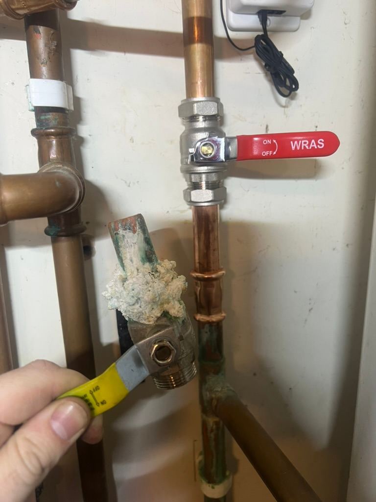A seized, limescaled valve held beside the new one replacing it